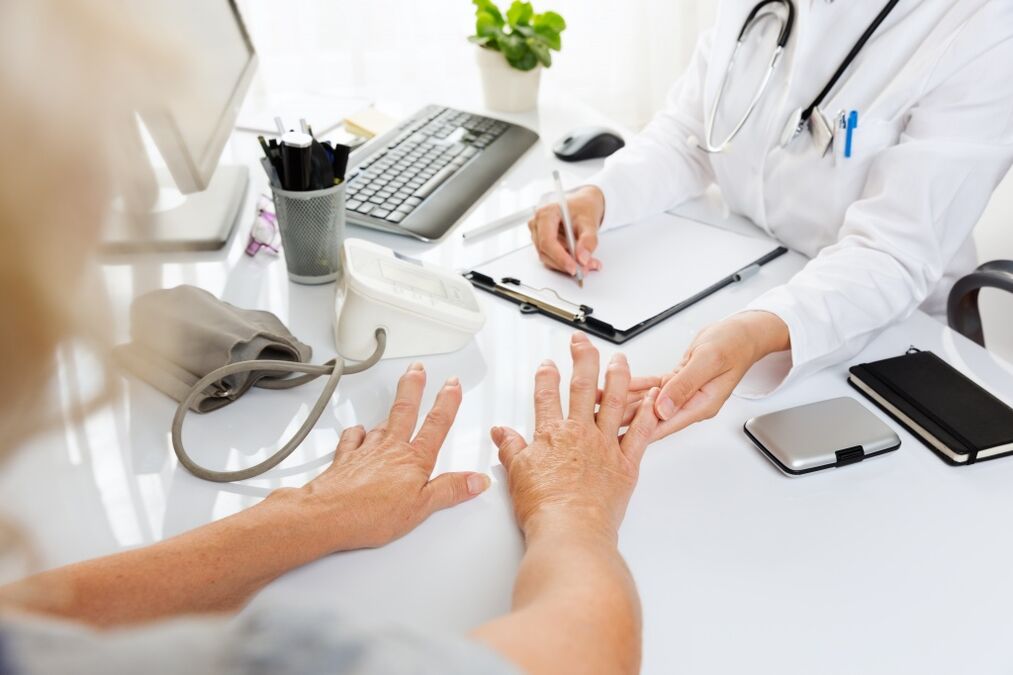 doctor examines the hands suffering fromarthritis